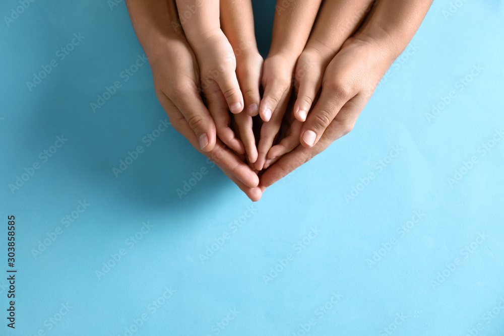 Mother holding hands with her children on blue background, top view. Happy family - obrazy, fototapety, plakaty 