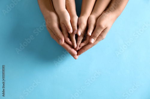 Mother holding hands with her children on blue background, top view. Happy family