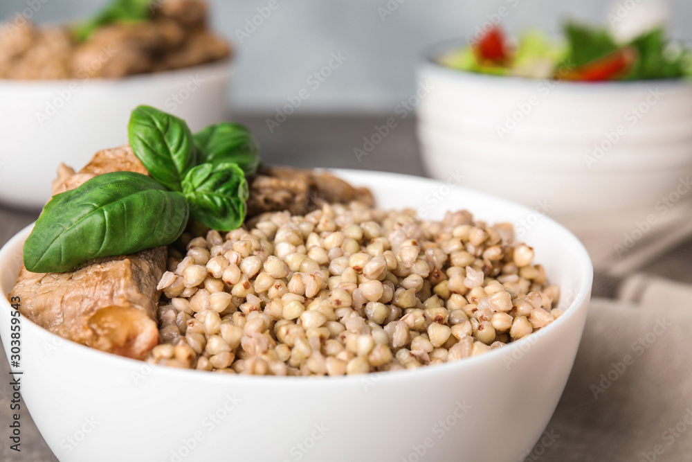 Bowl with tasty buckwheat porridge and meat, closeup