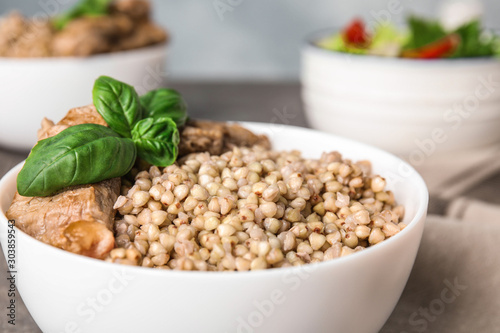 Bowl with tasty buckwheat porridge and meat, closeup