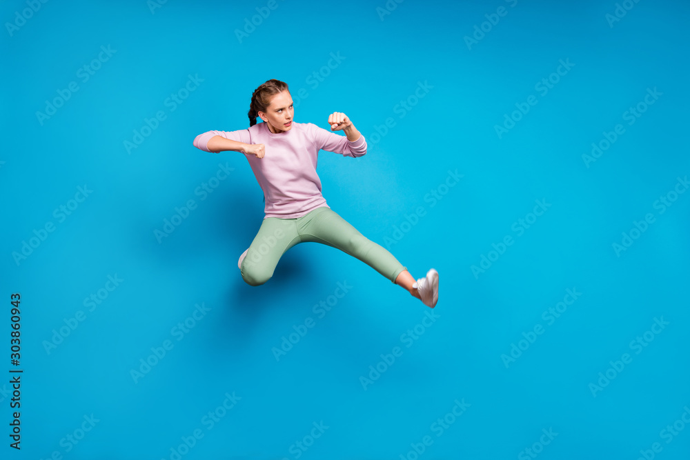Full length profile side photo of focused sportive girl train her kick boxing skills jump fight enemies wear stylish outfit white sneakers isolated over blue color background