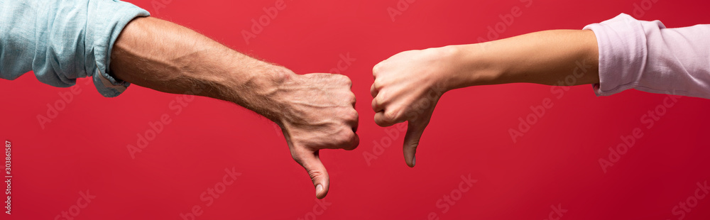 partial view of couple showing thumbs down, isolated on red - obrazy, fototapety, plakaty 