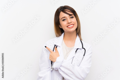 Young doctor woman over isolated background pointing to the side to present a product