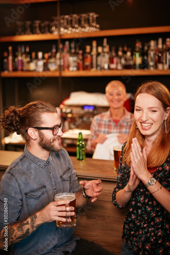 Group of friends drinking beer  chatting and having good time at pub. Night out.