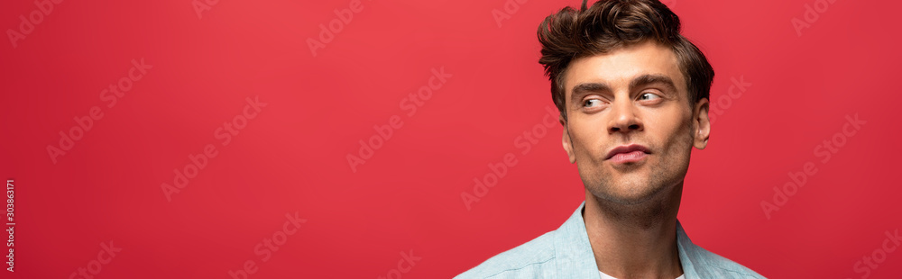 Fototapeta premium portrait of handsome pensive man in casual clothes isolated on red