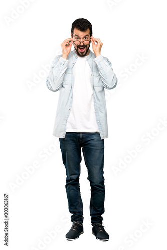 Full-length shot of Handsome man with beard with glasses and surprised over isolated white background