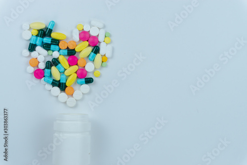 Assorted pharmaceutical medicine pills, tablets and capsules, and bottle on white background. Copy space for text, top view.