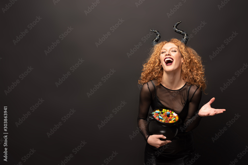 Ταπετσαρία laughing woman in maleficent costume holding pot with candies for halloween on b