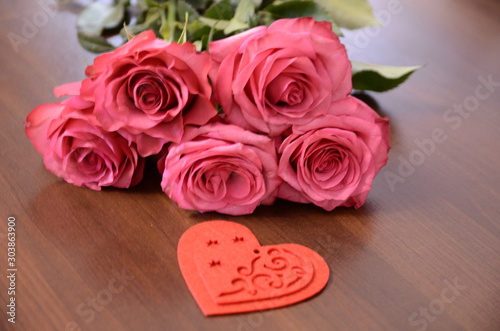 Valentine's Day, romance. A fresh bouquet of beautiful fragrant pink roses and a decorative red felt heart.