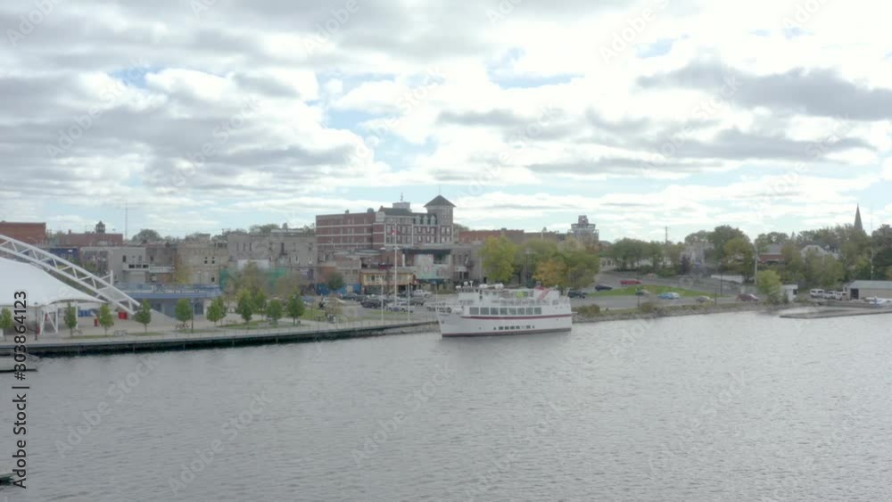 Flying around tour boat docked in the Lake of the Woods, Kenora, Ontario, Canada. parking lot and houses in the background. Panoramic view 4k drone footage from left to right. Flying around tour boat docked in the Lake of the Woods, Kenora, Ontario, Canada. parking lot and houses in the background. Panoramic view 4k drone footage from left to right.
