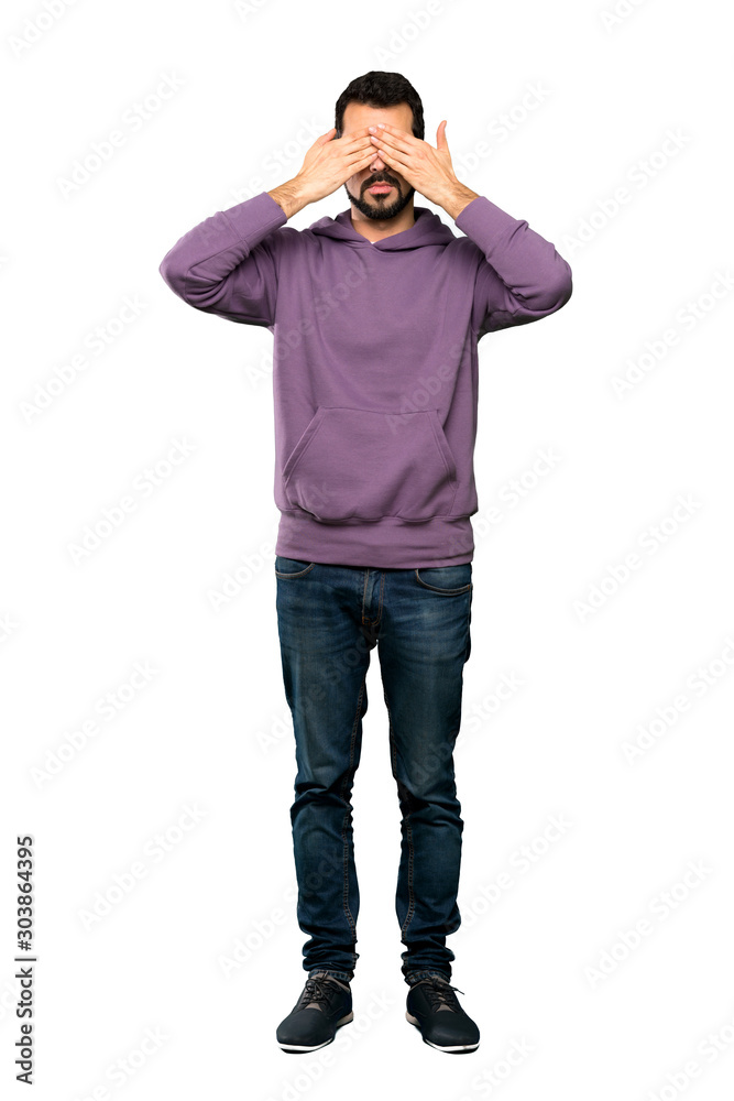 Full-length shot of Handsome man with sweatshirt covering eyes by hands over isolated white background Full-length shot of Handsome man with sweatshirt covering eyes by hands over isolated white background