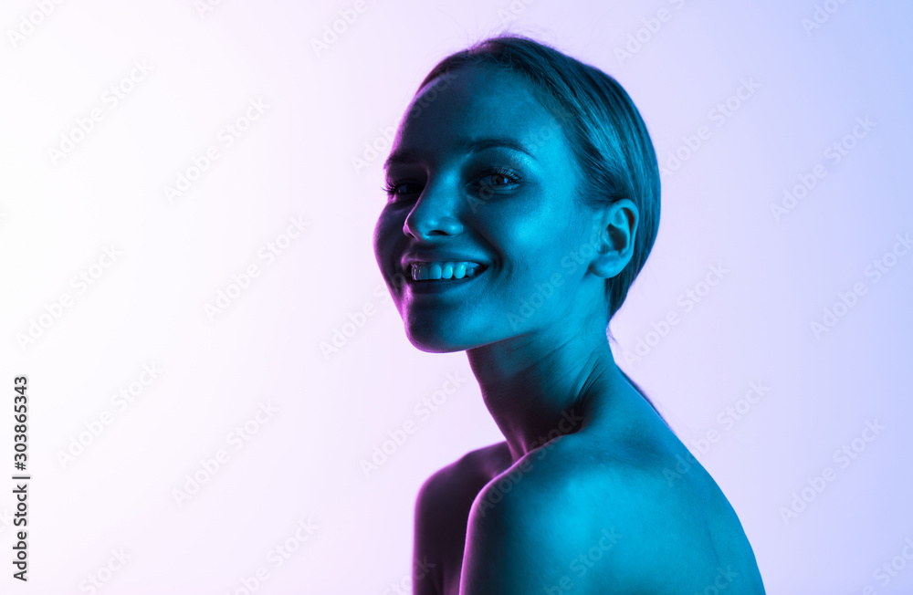 Portrait of beautiful young girl with clean skin on pretty face on neon light background