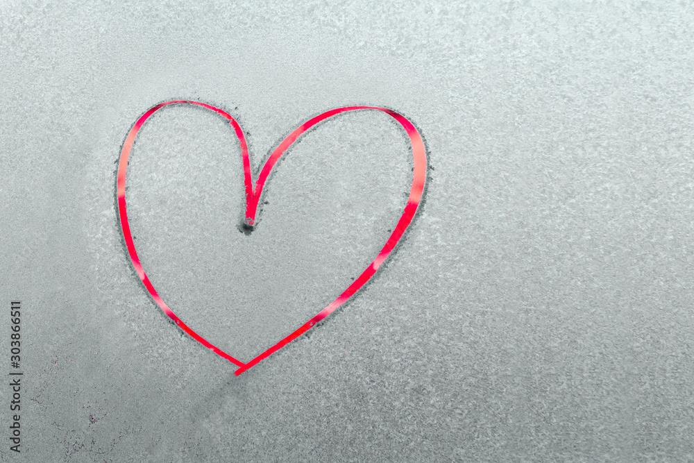 One beautiful bright red heart painted by finger on a frozen blue texture on a glass One beautiful bright red heart painted by finger on a frozen blue texture on a glass
