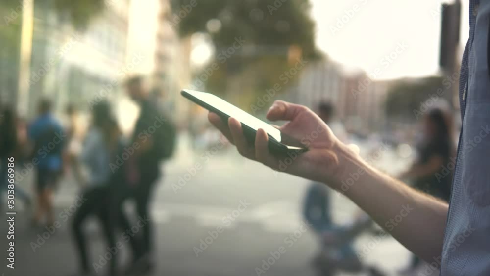Man student using a smart phone voice recognition function online walking on a city street, talking to mobile assistant. Tourist using smart phone voice recognition, dictates thoughts, voice dialing