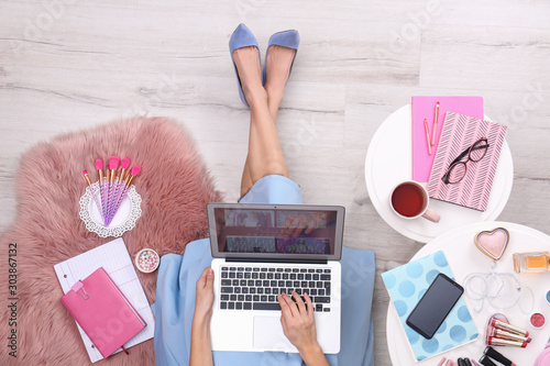 Beauty blogger with laptop and cosmetics sitting on floor, top view photo
