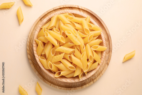 Pennoni pasta on beige background, flat lay