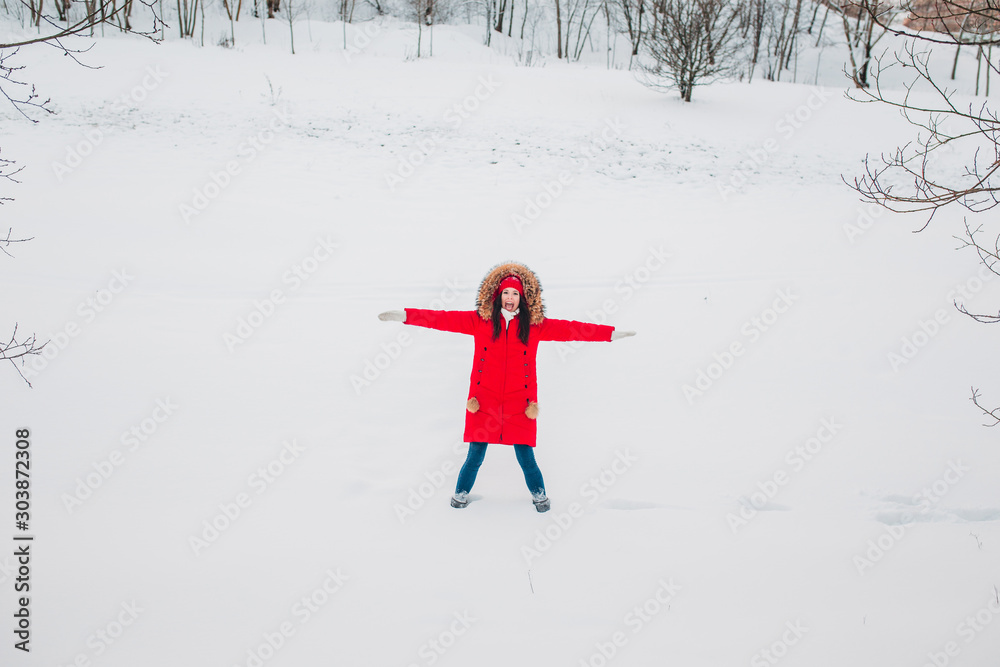 Young woman in red clothes playing with snow in winter park