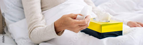 panoramic shot of ill senior woman holding napkin in bed