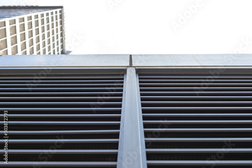 Tall building is shot from below. Blue sky and skyscraper and copy space. Horizontal and vertical lines as part of a multi-story building