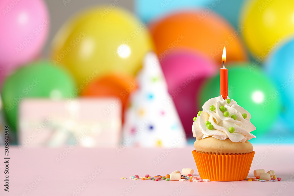 Birthday cupcake with candle on pink table against blurred background. Space for text Birthday cupcake with candle on pink table against blurred background. Space for text