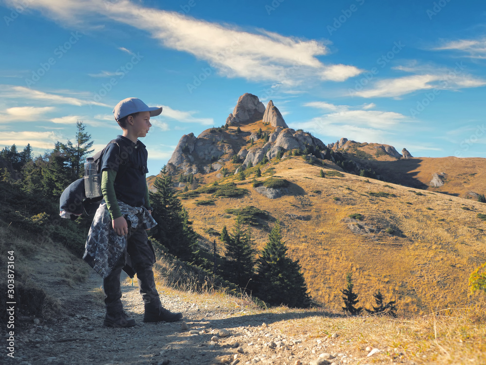 Little boy with backpack hiking in scenic mountains Little boy with backpack hiking in scenic mountains