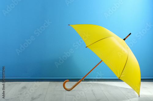 Beautiful yellow umbrella near blue wall. Space for text