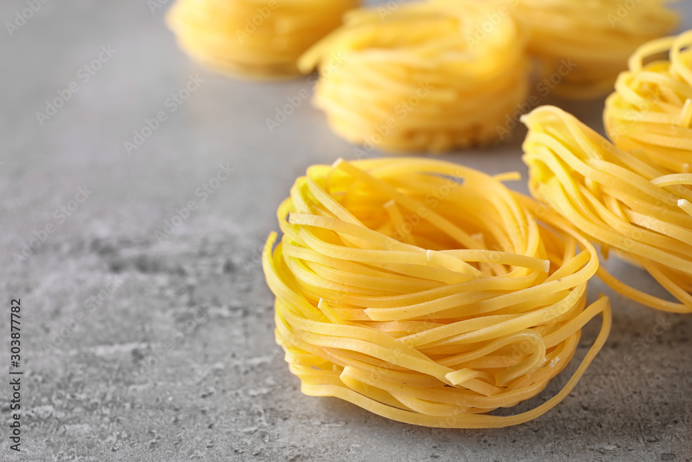 Uncooked angel hair pasta on grey table, closeup. Space for text Uncooked angel hair pasta on grey table, closeup. Space for text