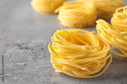 Uncooked angel hair pasta on grey table, closeup. Space for text