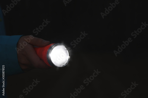 Man with bright flashlight at night, closeup. Space for text