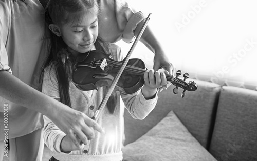 Teacher teaching little girl for playing violin music class,at studio music room,with happy feeling,blurry light aorund,Lens flare effect,black and white tone photo