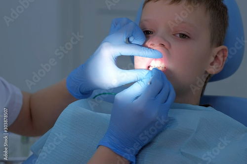 Fotografie Dentist making fluoridation of child boy teeth after cleaning for protection
