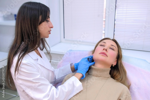 Doctor cosmetologist making injection with filler in mature woman patient cheek on face to moisturize and rejuvenate skin. Beauty procedure against wrinkle in clinic. Preparation with hyaluronic acid.