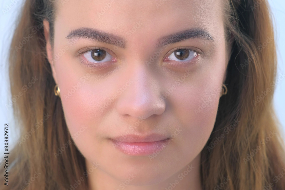 Portrait of beautiful young girl before beauty procedure of permanent eyeliner in cosmetology clinic. Face closeup view. Woman is looking at camera on white background, front view. Portrait of beautiful young girl before beauty procedure of permanent eyeliner in cosmetology clinic. Face closeup view. Woman is looking at camera on white background, front view.