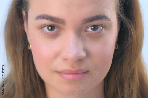 Portrait of beautiful young girl before beauty procedure of permanent eyeliner in cosmetology clinic. Face closeup view. Woman is looking at camera on white background, front view.