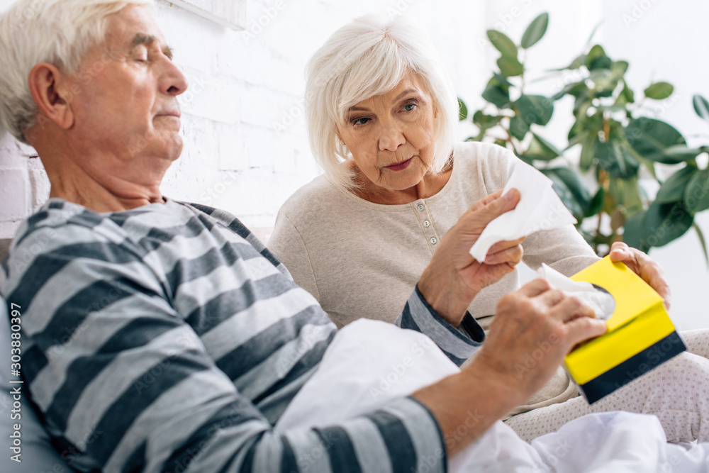 attractive wife giving napkins to ill husband in bed attractive wife giving napkins to ill husband in bed