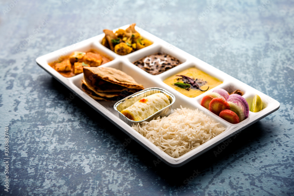 Indian vegaterian Food Thali or Parcel food-tray with compartments in which paneer, dal makhani / parka, aloo-gobi sabji, chapati and rice with Bengali sweet served Indian vegaterian Food Thali or Parcel food-tray with compartments in which paneer, dal makhani / parka, aloo-gobi sabji, chapati and rice with Bengali sweet served