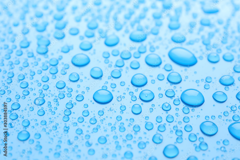 Water drops on light blue background, closeup view