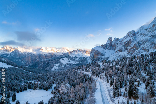 Aerial view of Curved road in the snowy mountains of Italian Alps in South Tyrol with dolomites in background / Sunny winter day with harsh shadows and lot of snow © valdisskudre