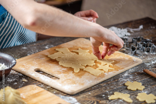 Woman rolls out the dough with a rolling pin and shapes gingerbread. Christmas mood for cooking delicious cookies.