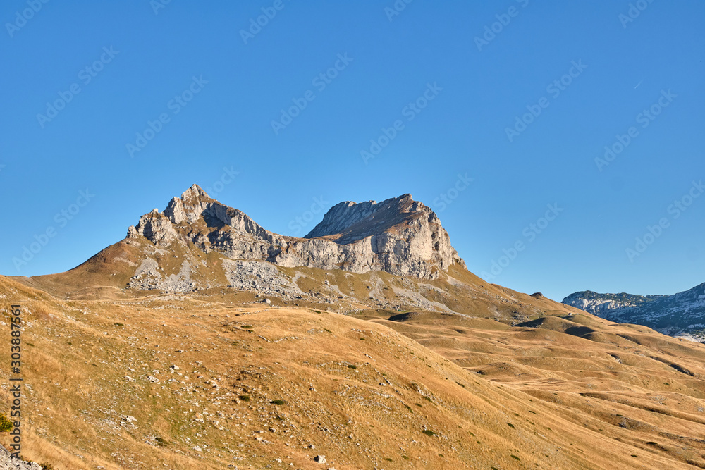 Rocky mountains covered with autumn meadow against the blue sky