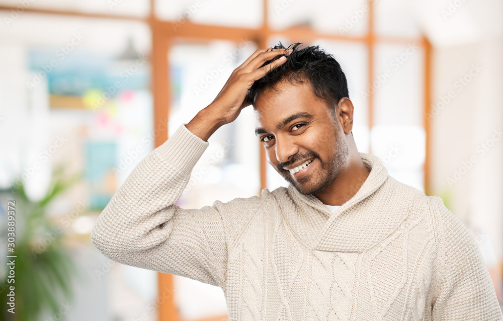 emotion, expression and people concept - smiling indian man in knitted  woolen sweater touching his hair over office background Stock Photo | Adobe  Stock