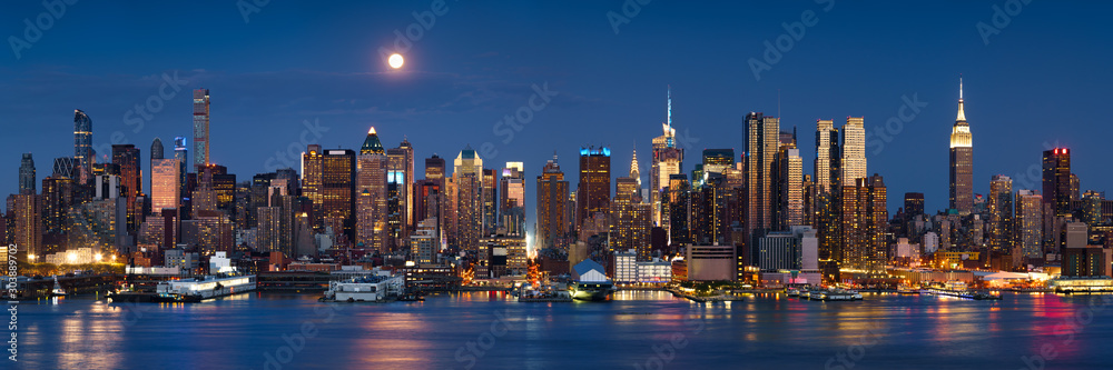 Fototapeta premium Moonrise over skyscrapers of Midtown Manhattan West at dusk from across the Hudson River. New York City, NY, USA