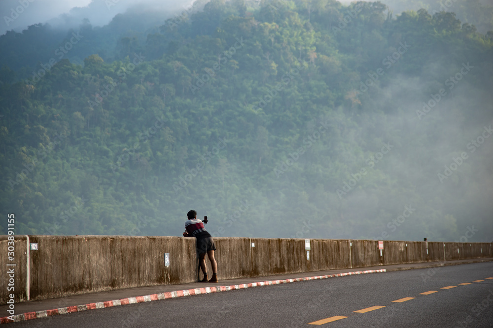 Lonely man stand with mountain in foggy background and asphalt road