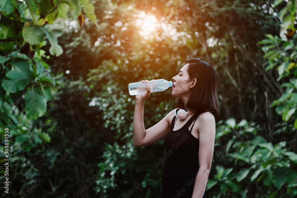 Beautiful asian woman drinking water after work out exercising at summer green park. Beautiful asian woman drinking water after work out exercising at summer green park.