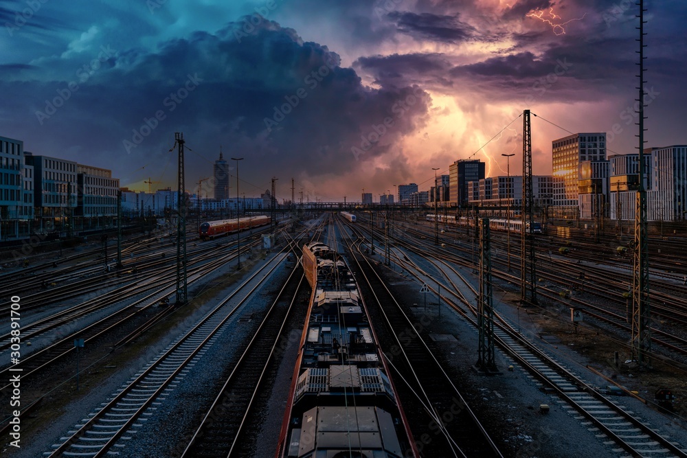 Bahnhof mit Zügen und Gewitter am Himmel