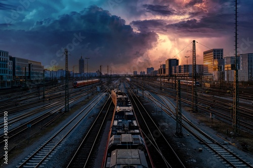 Bahnhof mit Zügen und Gewitter am Himmel