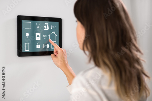 automation, internet of things and technology concept - woman using tablet pc computer at smart home