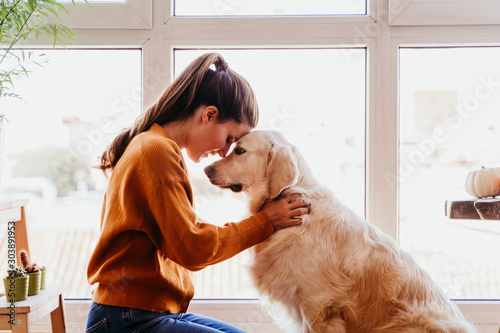 close up of beautiful woman hugging her adorable golden retriever dog at home. love for animals concept. lifestyle indoors