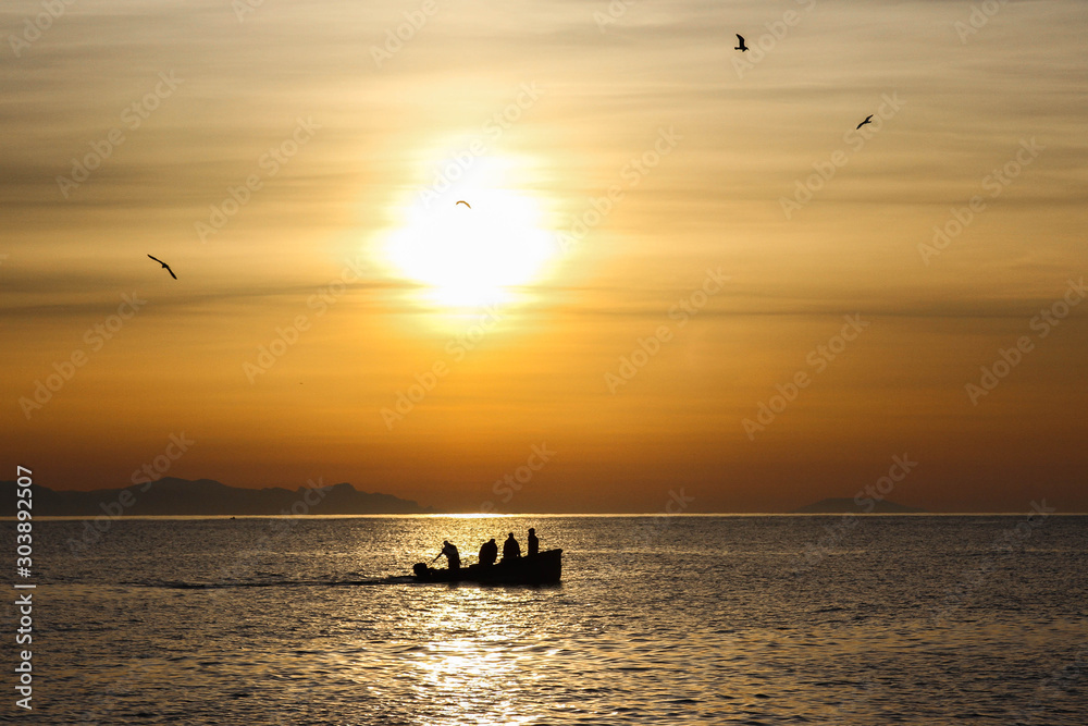 fishing boat and seagulls on sunrise background during sunrise over the baltic sea in gdynia, poland