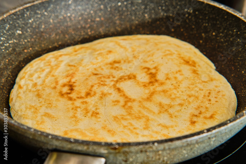 Cooking big pancake on frying pan
